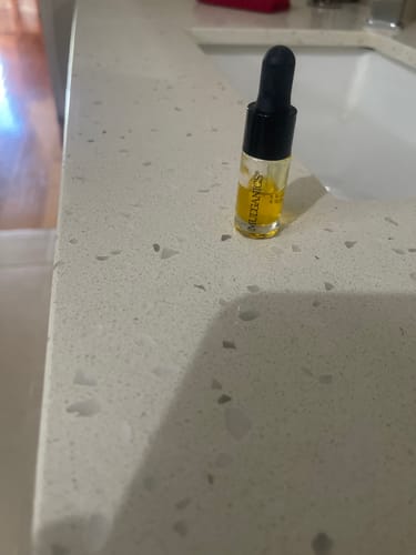 Customer's trial-size SEA BUCKTHORN SERUM bottle with yellow oil on a bathroom counter.
