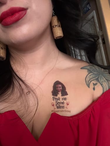 Close-up of a reviewer wearing the custom 'Pour Me Some Wine' temporary tattoo on their chest.