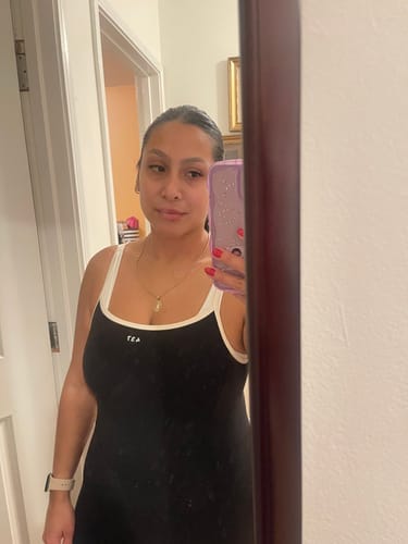 Reviewer's mirror selfie showing the fit of the black Onesie with its contrast cream straps and tank style.