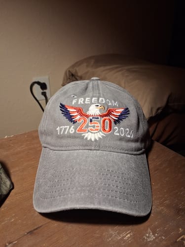 Customer's gray Freedom 250th Hat with an embroidered eagle, shown up-close on a wooden table.
