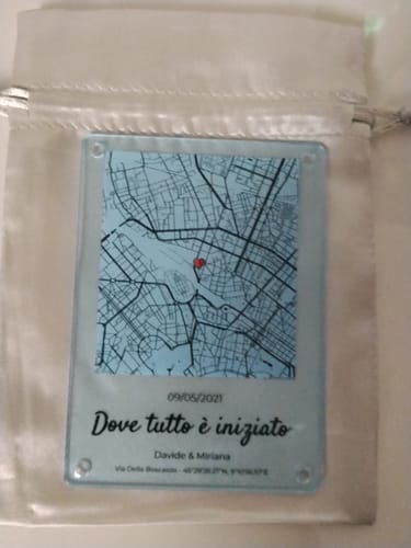 Personalisierter Acrylmagnet eines Kunden mit blauer Karte, der auf seinem weißen Beutel liegt.
