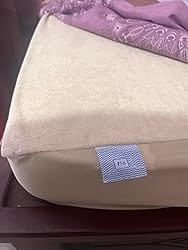 Customer's beige Flo mattress protector fitted on the corner of a mattress, showing the terry cloth texture.