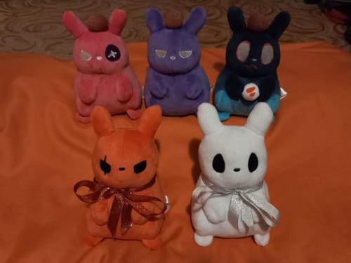 Customer's collection of five colorful Rain World Slugpup plushes arranged on an orange blanket.