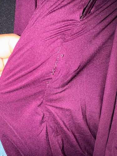 Customer's close-up of the purple Naked Closed Toe Jumpsuit showing damaged stitches and loose threads along a seam.