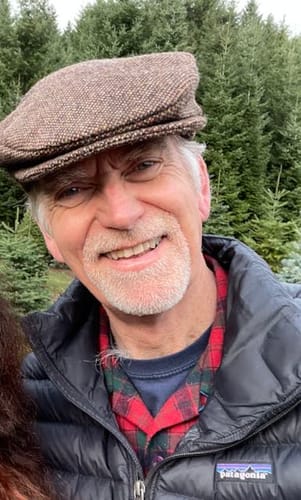 Reviewer smiling while wearing the brown Vintage Cap Ear Flap Tweed outdoors with the flaps tucked in.