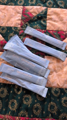 Customer shows several Migranium stick packs spread across a colorful quilt.