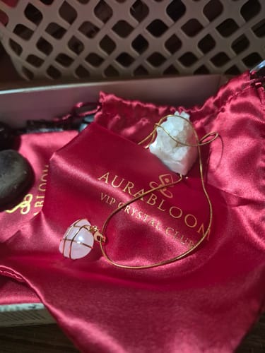 Customer's wire-wrapped rose quartz heart necklace on a thin chain, resting on its red satin brand pouch.