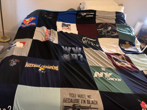 Customer's large Premium T Shirt Quilt, made from various t-shirts, spread across a bed in a bedroom.