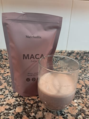 Cliente mostrando el paquete de Maca Latte junto a un vaso con la bebida cremosa ya preparada.