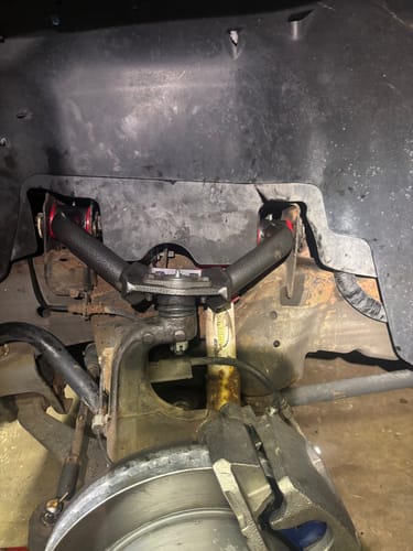 Customer's black KSP Upper Control Arm with red bushings installed in the wheel well of a truck.