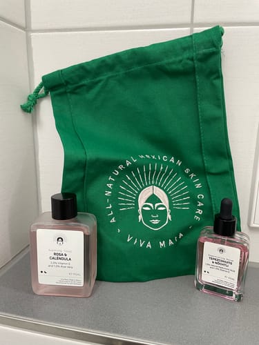 Reviewer's green Cotton Bag shown on a counter with two skincare products in front of it.