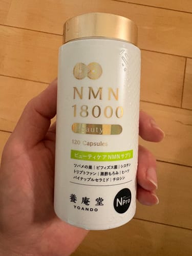 レビュアーが手に持っている「養庵堂 NMN18000 Beauty」の白いボトル。
