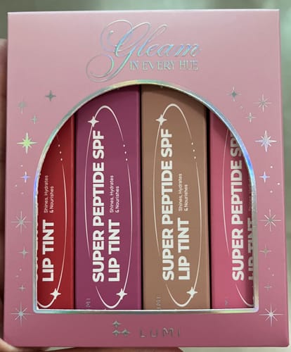 Reviewer holding the Holiday Hues Bundle in its pink festive packaging, with four Super Peptide SPF Lip Tints visible.