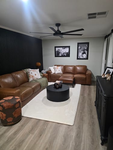 Customer's soft Vanilla Cream Mellow Mat in their cozy living room with brown leather sofas and a black accent wall.