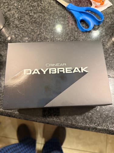 Customer's view of the sleek black box for the CrinEar Daybreak In-Ear Headphones on a countertop.