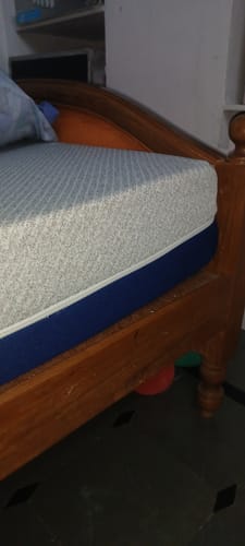 Close-up of the customer's Flo Anti-Gravity™ Mattress, showing the grey top cover and blue side, on a wooden bed frame.