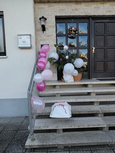 Kunde zeigt das verpackte Leonardo Gläser Set als Geschenk auf einer Treppe.