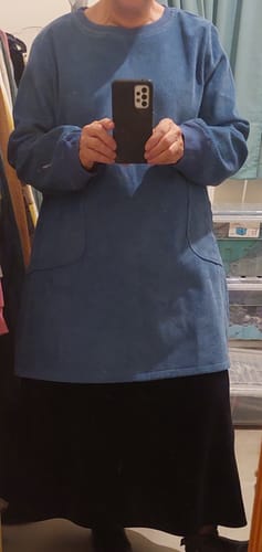 Reviewer taking a mirror selfie in the blue fleece-lined corduroy dress, showing its pockets.