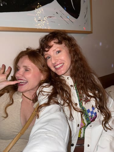 Reviewer with full, wavy red hair smiling next to a friend after using the Hidden Waterfall™ Shampoo Bar.