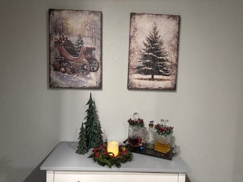 Reviewer's two vintage Christmas wall art canvases hung together over a console table with holiday decor.