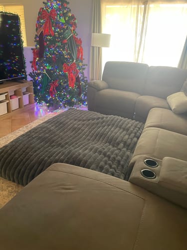 Customer's large, dark grey Muscle Mat CloudPad on the floor of a living room next to a couch.