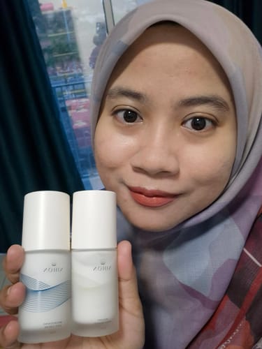 Customer smiling while holding two bottles of Instant Pore Eraser, showcasing her smooth, clear skin.