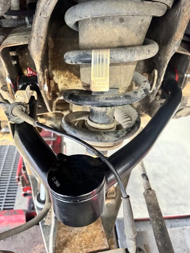 Close-up of a customer's black OE Upgrade Upper Control Arm installed on a truck suspension.