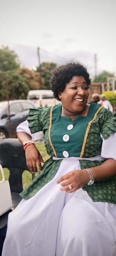 Reviewer smiling outdoors while wearing the short, natural-looking Brazilian Curly Afro wig.