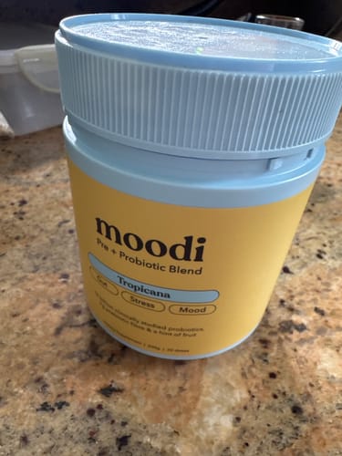 Customer's yellow container of moodi Pre + Probiotic Blend with a light blue lid on a granite counter.