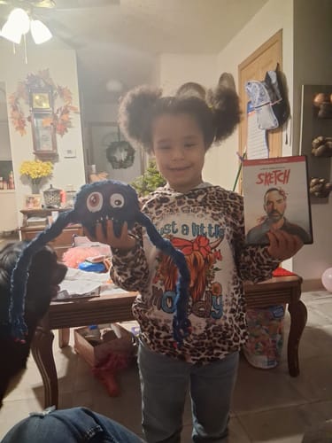 A happy customer holding up the blue SKETCH Dave Plushie and the matching movie case.