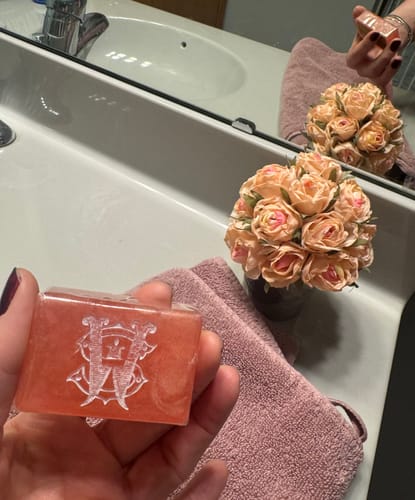 Customer holding the shimmery, travel-size Oud Harmony soap bar in a bathroom setting.