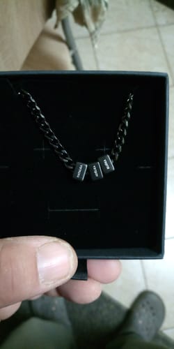 Customer holds the black Legacy Necklace in its box, showing three personalized name beads.