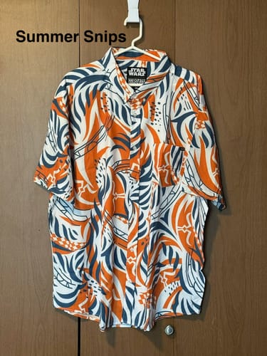 Customer's 'Summer Snips' shirt hanging on a hanger, showing its bold orange and blue pattern.