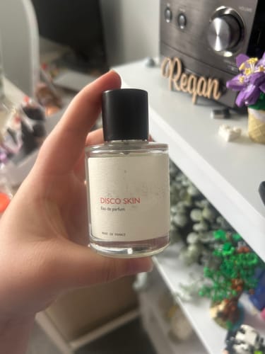Customer holding a clear bottle of Disco Skin perfume in their hand, showing the label.