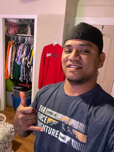 Reviewer smiling while wearing the dark Adventure Tee with a mountain graphic indoors.