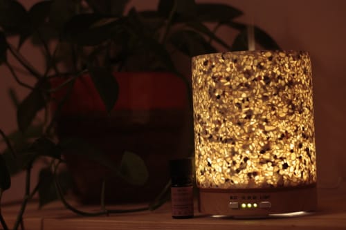 Kundenfoto des ätherischen Öls Glow & Flow neben einem warm leuchtenden Aroma-Diffusor.