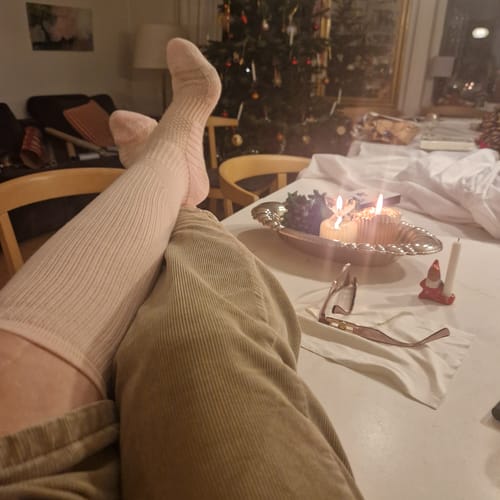 Anmelder slapper af med benene oppe på et bord iført lyserøde, lange støttestrømper i en hyggelig julestue.