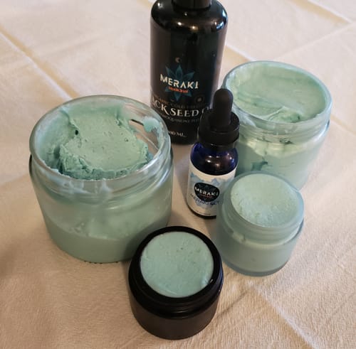 Reviewer's Meraki Blu Methylene Blue bottle next to jars of light blue balm created with the product.