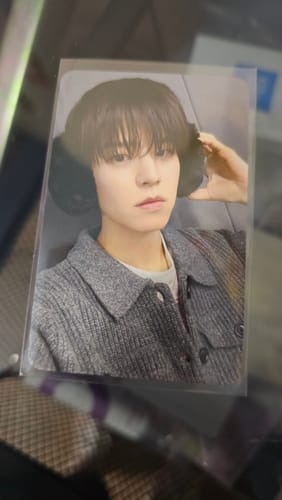 Customer's close-up of a STRAY-KIDS photocard showing a member wearing black earmuffs and a grey jacket.