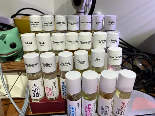 Reviewer's large collection of small perfume bottles, including Paradise Eden, on a desk.