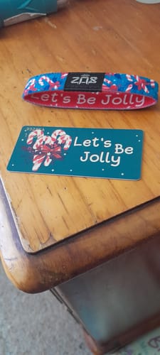 Customer's colorful 'Let's Be Jolly' Bracelet and its matching card displayed on a wooden table.