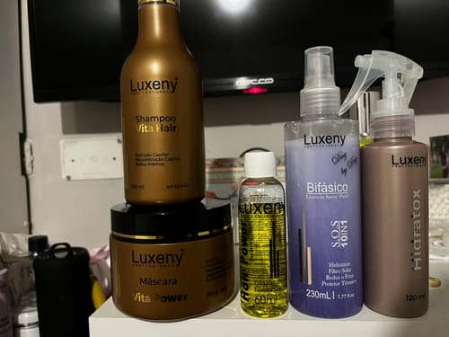 Cliente muestra varios productos de Luxeny, incluido el Kit Reparación Capilar S.O.S., en una estantería.