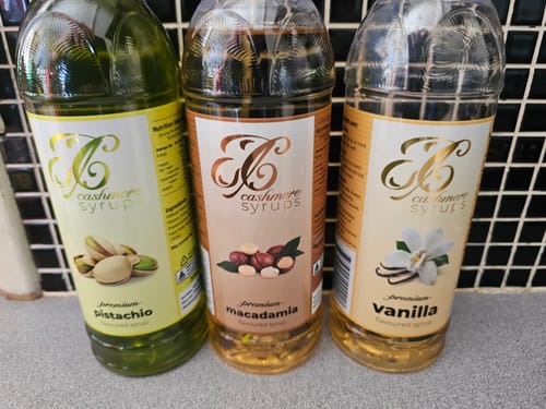 Customer's Pistachio Syrup bottle next to Macadamia and Vanilla syrup bottles.