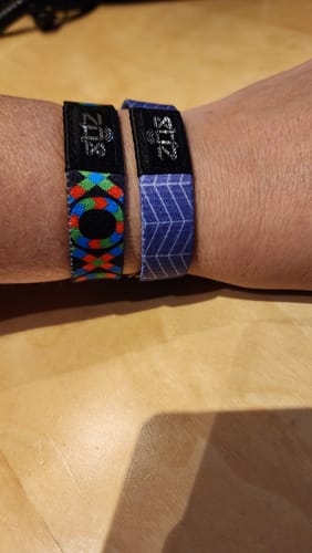 Customer wearing two ZOX bracelets on their wrist, one with a colorful geometric pattern and the other with a purple pattern.