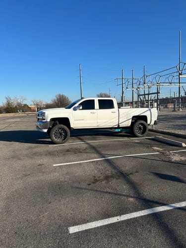 Reviewer's white lifted Silverado showing the installed Traction Bar Kit with a blue light underneath.