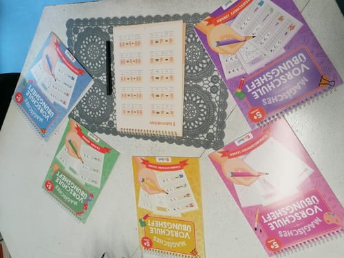 Kunde zeigt das Geschenk-Starterset der Edubini Magische Übungshefte, ausgebreitet auf einem Tisch.