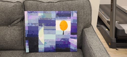 Customer's completed Harbinger of Autumn painting resting on the arm of a gray sofa.