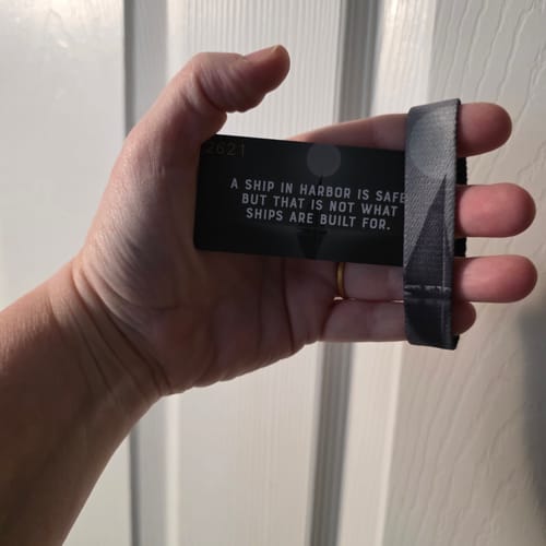 Reviewer holding the 'A Ship In Harbor Is Safe' bracelet alongside its matching card, which displays the full quote.