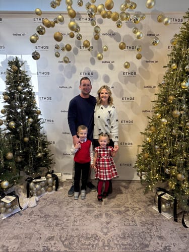 Reviewer wearing the Bow Accented Ribbed Trim Sweater while posing with her family for a holiday photo.