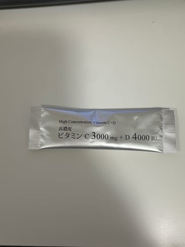 レビュアーによる、ビタミンC+Dの銀色の個包装。白い平面に横向きに置かれている。